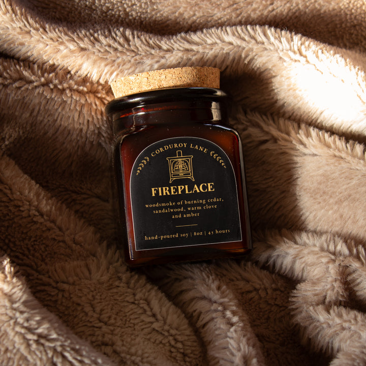 Jar of 'Fireplace' candle by Corduroy Lane Candles on a textured fabric surface