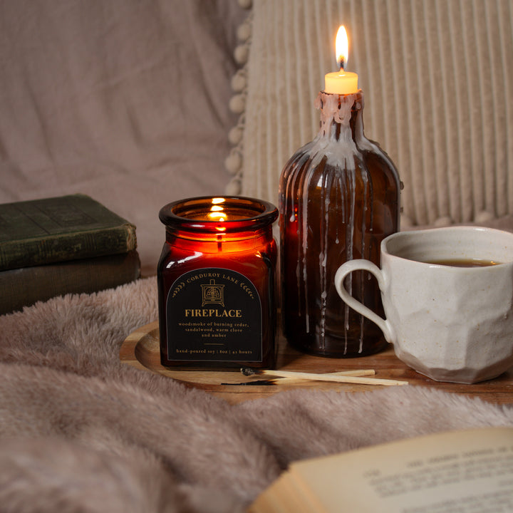 Candle, bottle, and cup on a wooden surface with a soft background