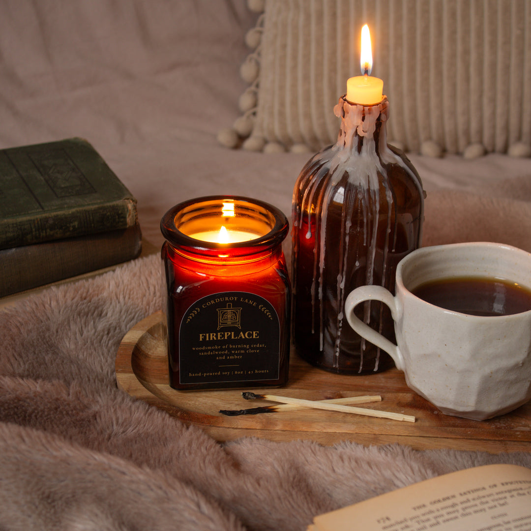 Candlelit scene with a lit candle, book, and cup of coffee on a wooden tray.