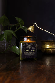 Forest Fog: a cozy spooky candle from Corduroy Lane in a green glass square apothecary jar with a cork lid, scented in a refreshing, masculine blend of misty ozone and woodlands with lavender, mint, and juniper for lovers of all things cozy and bookish