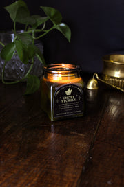 Ghost Stories: a spooky halloween candle from Corduroy Lane in a green glass square apothecary jar with a cork lid and a black and gold label, scented in a refreshing, masculine blend of misty ozone and woodlands with lavender, mint, and juniper for lovers of all things cozy and spooky