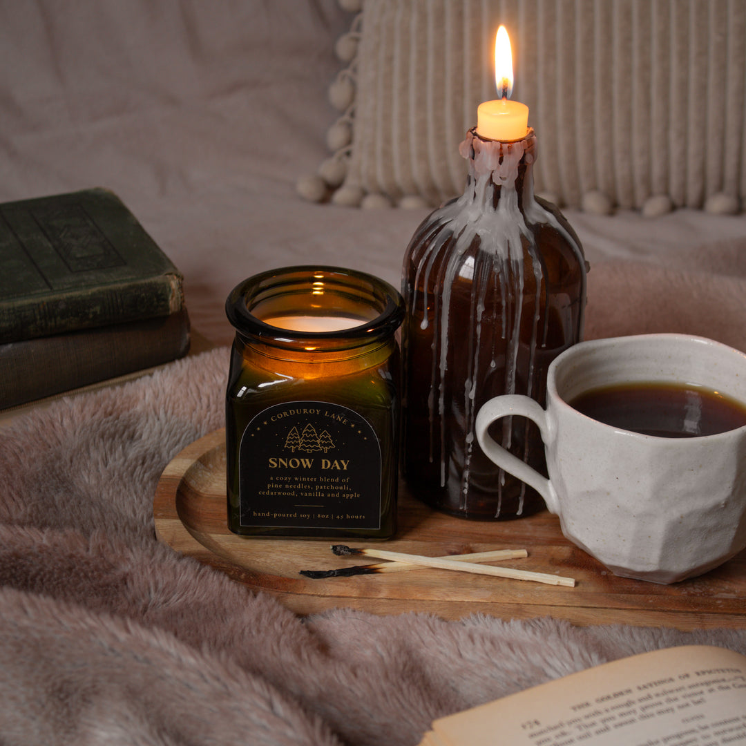 Candlelit scene with a cup of coffee, book, and decorative items on a wooden tray.