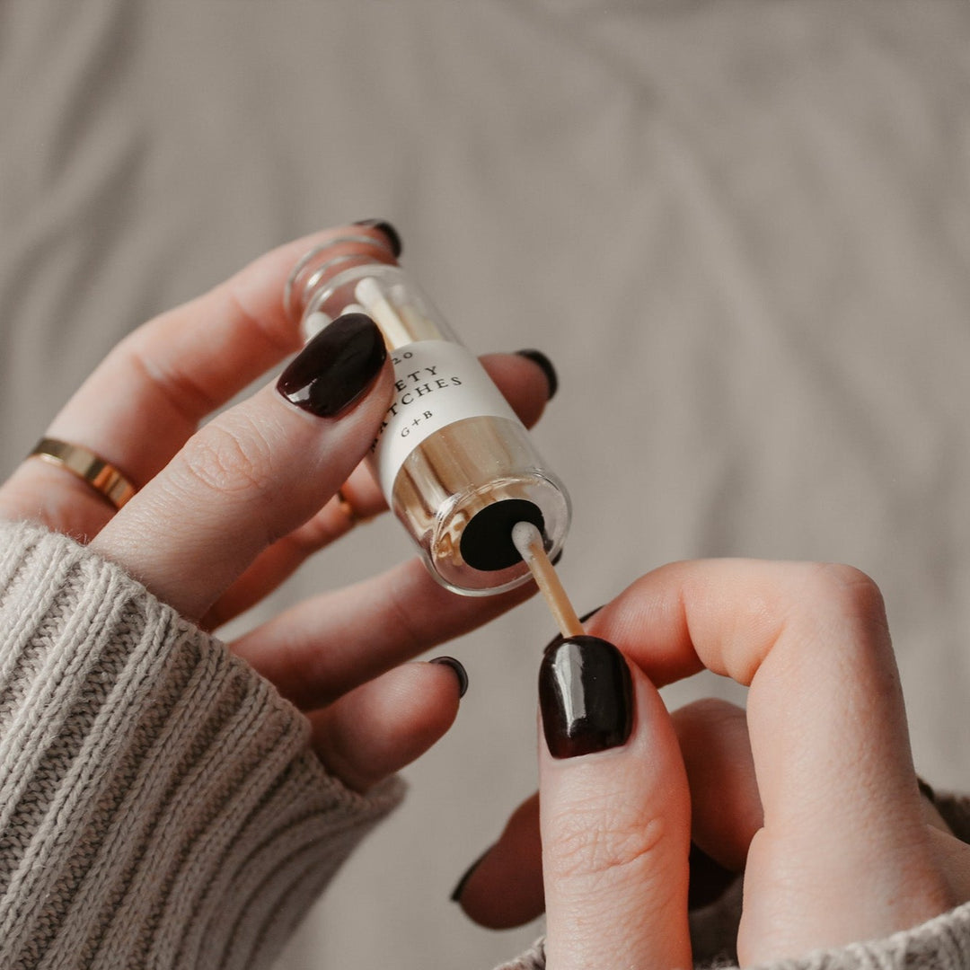 Hands holding a glass bottle of matches with a cork lids with 20 safety matches. They are showing that they have a match striker on the bottom of the bottle