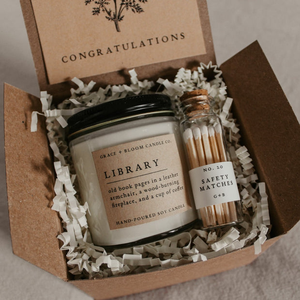 A cozy gift box from Grace and Bloom is perfect for bookish friends, has a candle in your choice of literary scents, a glass bottle of matches, and has a removable kraft-colored card with a floral design and your choice of messages on it.