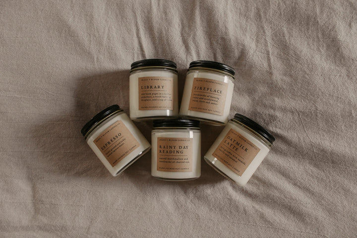 Five Corduroy Lane candles with labels on a textured surface