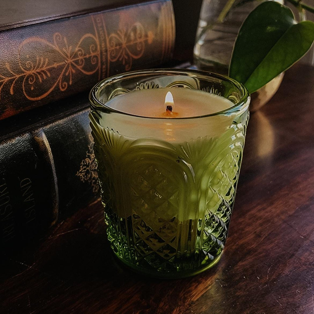 Garden Mint scented candle in a textured green glass jar on a wooden surface with a plant in the background