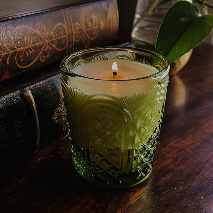 Garden Mint scented candle in a textured green glass jar on a wooden surface with a plant in the background