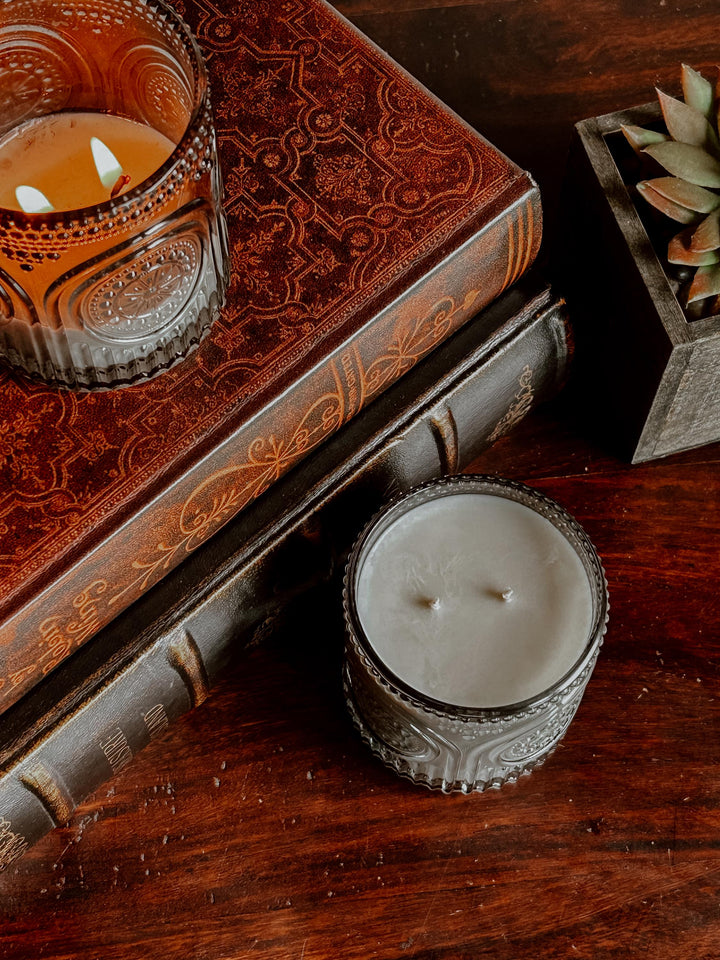 Decorative candles on ornate books with a wooden surface background
