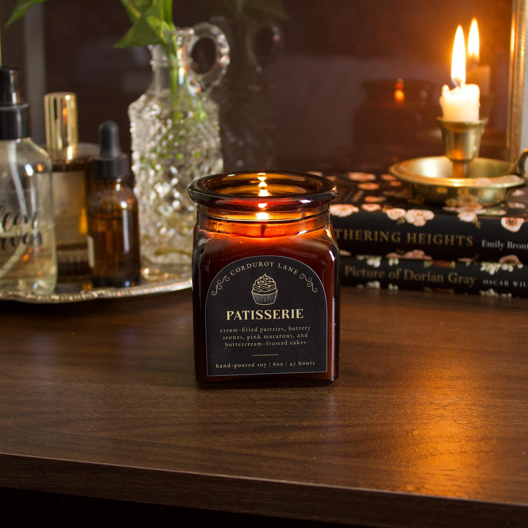 Candle labeled 'Patisserie' on a wooden surface with a dark background