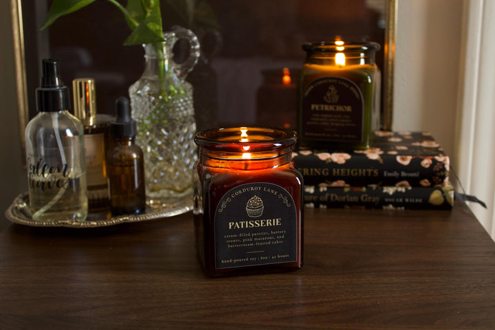 Candle labeled 'Patisserie' on a table with other decorative items.