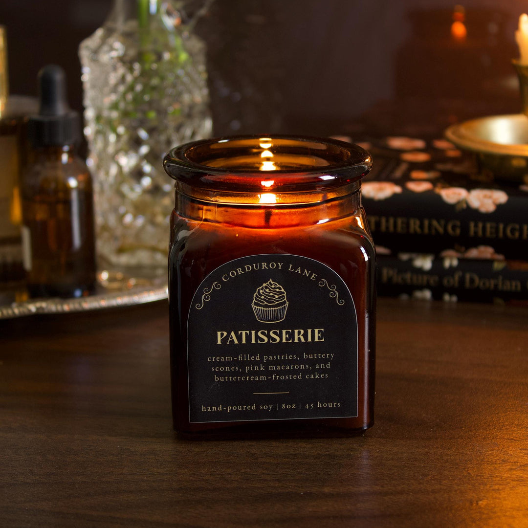 Candle labeled 'Patisserie' on a wooden surface with a blurred background