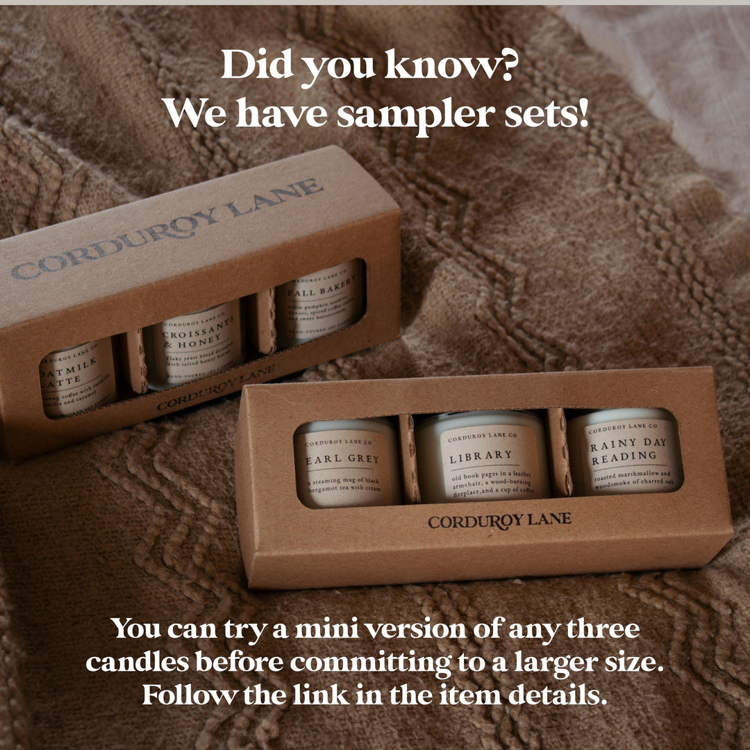 Two cardboard boxes of Corduroy Lane candles on a textured brown surface with promotional text.