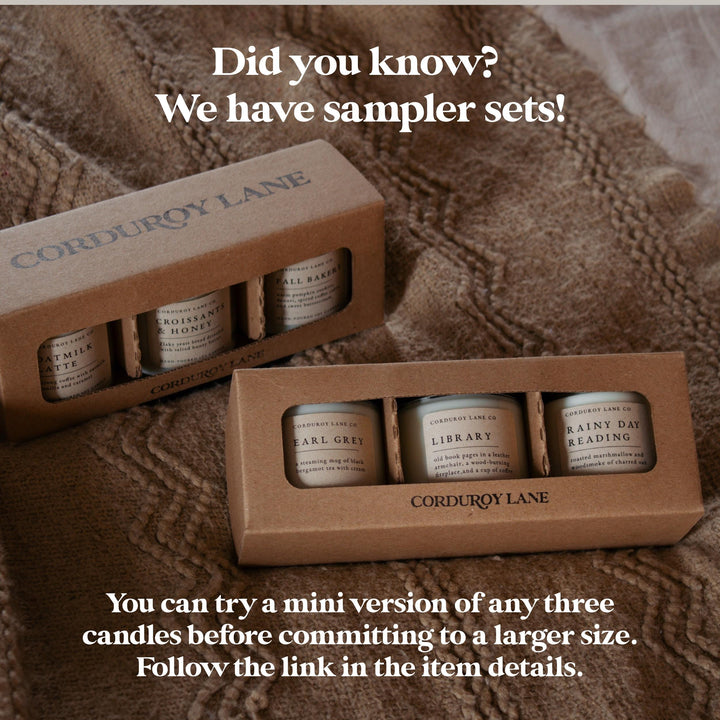 Two cardboard boxes of Corduroy Lane candles on a textured brown surface with promotional text.